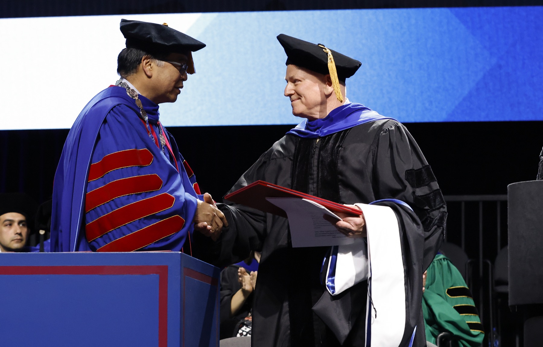 Robert Holland, accepted the posthumous honorary degree on behalf of his wife, Lori Holland, at the Kellstadt Graduate School of Business ceremony.